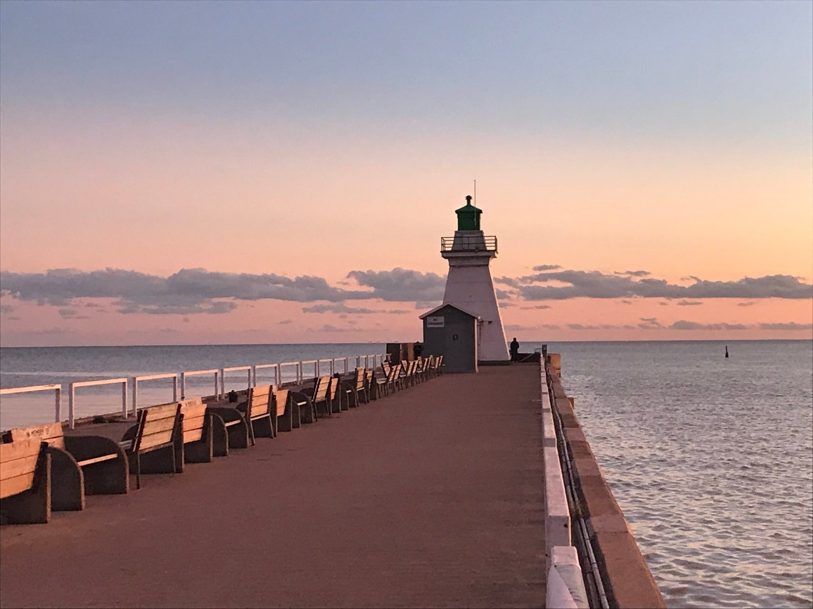 Benches along the Port Dover pier leading to the harbour light at sunset